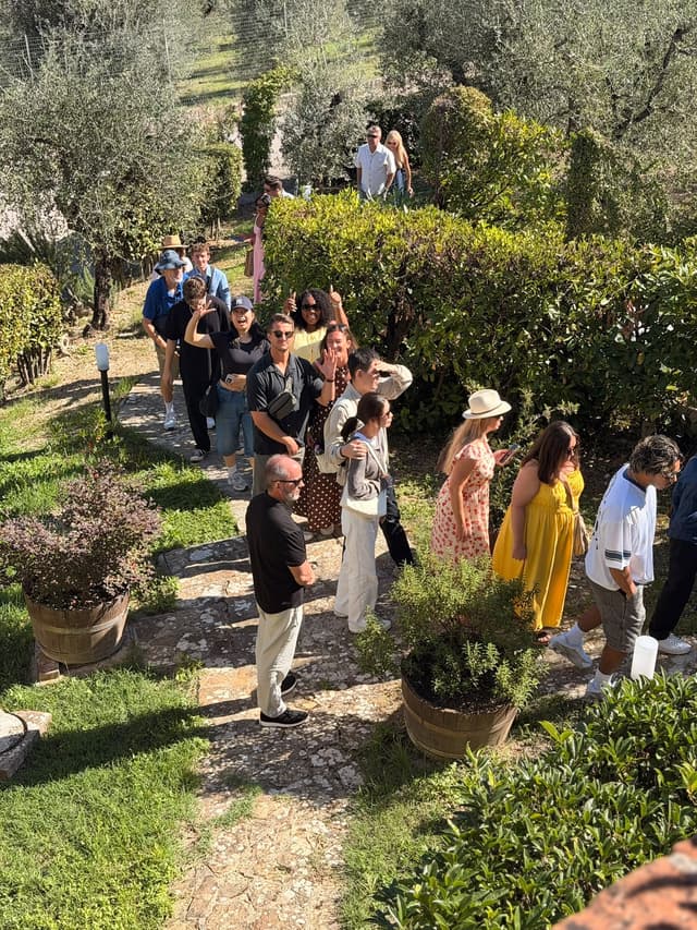 Tour group walking the stone path through the olive grove of a Tuscan wine estate