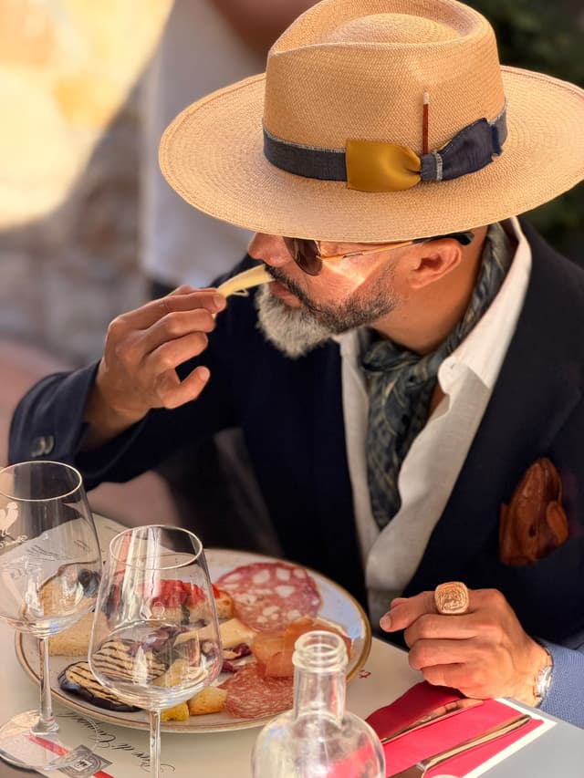 Guest in a straw hat tasting a sliver of pecorino from the antipasto board