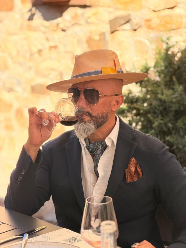 Guest in a straw hat and linen jacket tasting a glass of Chianti Classico