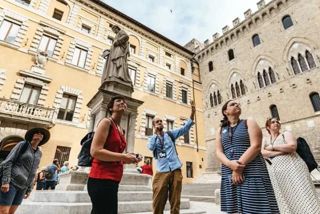 A guide pointing out details of Palazzo Salimbeni to a small group in Siena