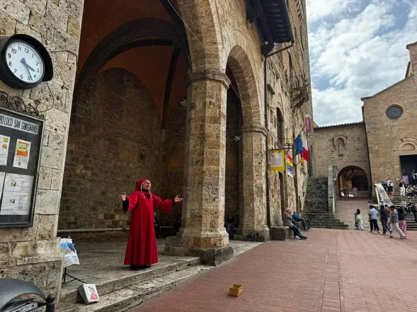 A street performer dressed in red under the arches of San Gimignano